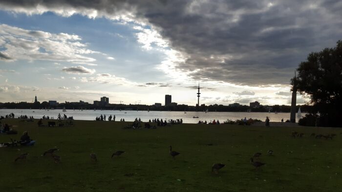 Aussicht von Ostufer auf Westufer der Außenalster, Hamburg, Skyline ist im Schatten.